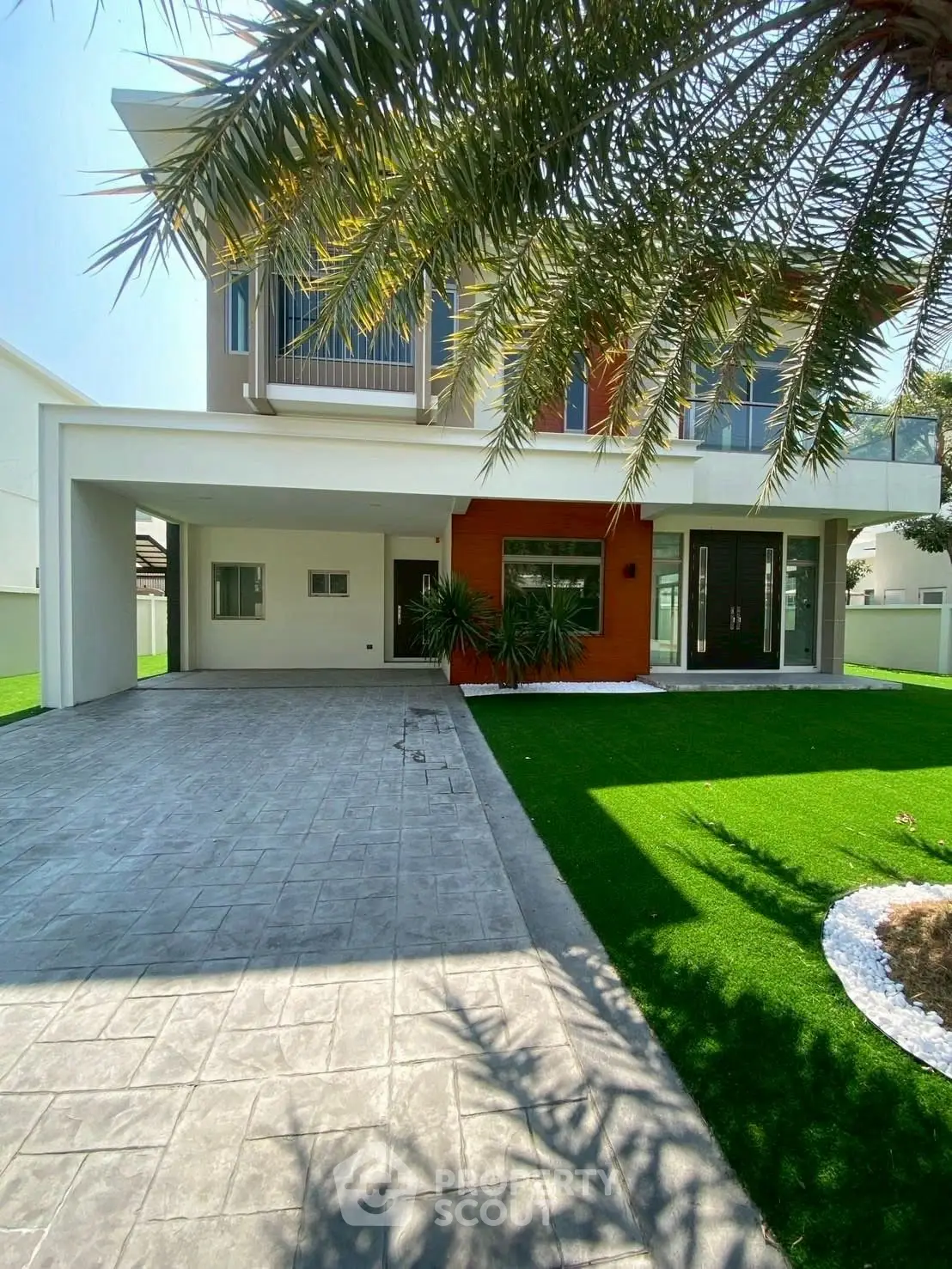 Modern two-story house with lush green lawn and spacious driveway