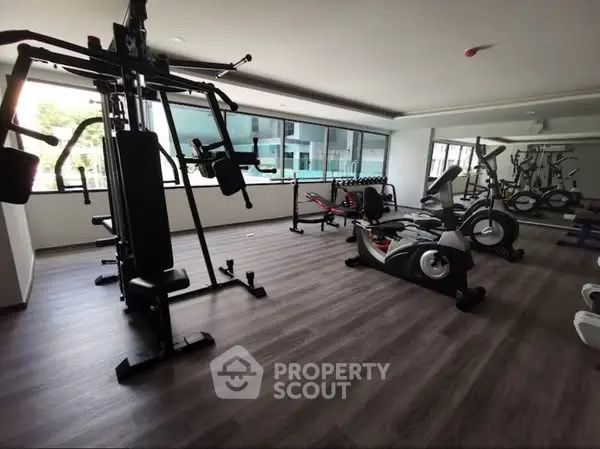Modern gym with state-of-the-art equipment and large windows in a residential building.
