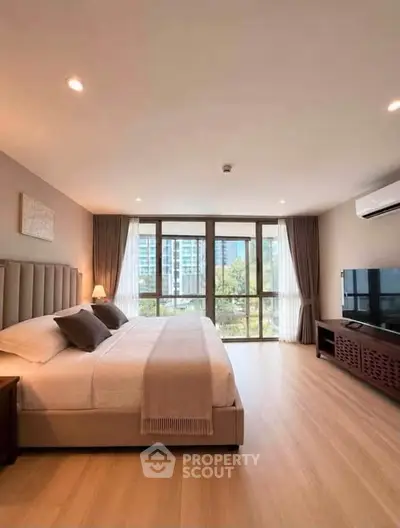 Spacious modern bedroom with large windows and elegant decor in a high-rise apartment.