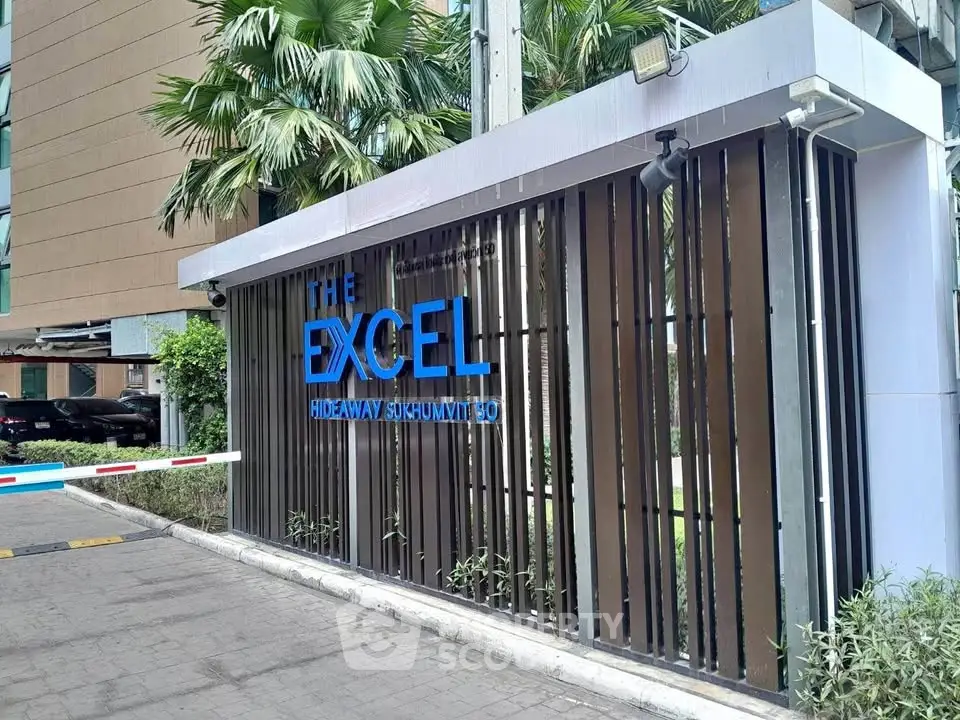 Modern entrance of The Excel Hideaway Sukhumvit 50 with sleek design and lush greenery.