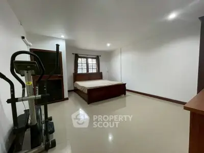 Spacious bedroom with exercise equipment and modern furnishings in a well-lit room.