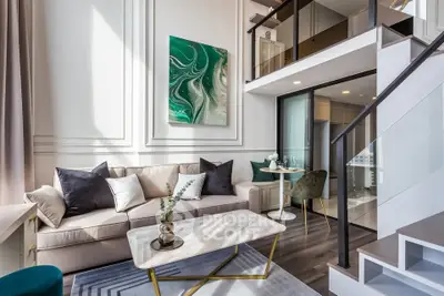 Luxurious modern living room with high ceilings and mezzanine, featuring elegant decor and natural light.