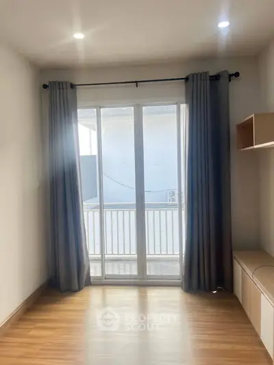 Bright room with large window and wooden floor, ideal for cozy living space.