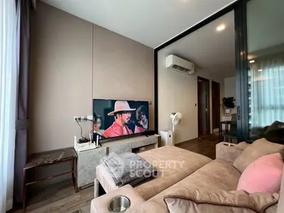 Modern living room with cozy sofa and large TV, featuring stylish decor and air conditioning.