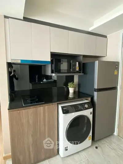 Modern compact kitchen with sleek appliances and stylish cabinetry in a contemporary apartment.