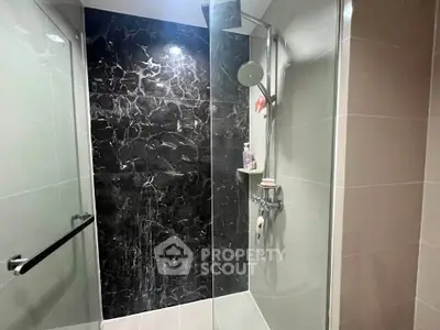 Modern bathroom with sleek black marble shower and contemporary fixtures.