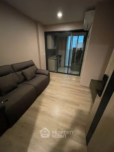 Cozy living room with modern sofa and sliding glass doors leading to a compact kitchen.