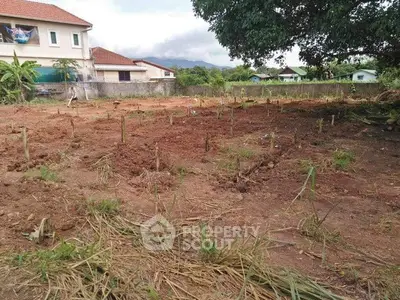 Spacious plot of land with potential for development, surrounded by greenery and residential homes.