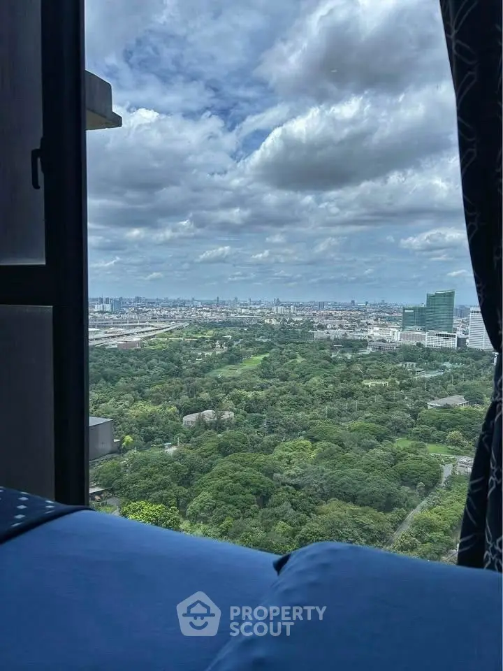 Stunning cityscape view from a high-rise apartment window overlooking lush greenery and skyline.