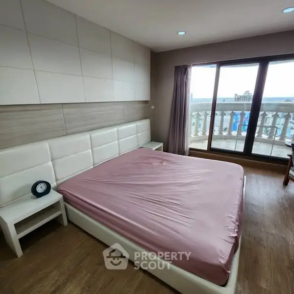 Spacious bedroom with large windows and balcony access in modern apartment.