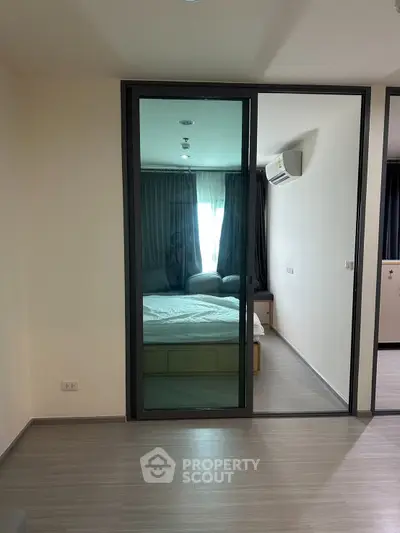 Modern bedroom with glass sliding door and air conditioning in a stylish apartment.
