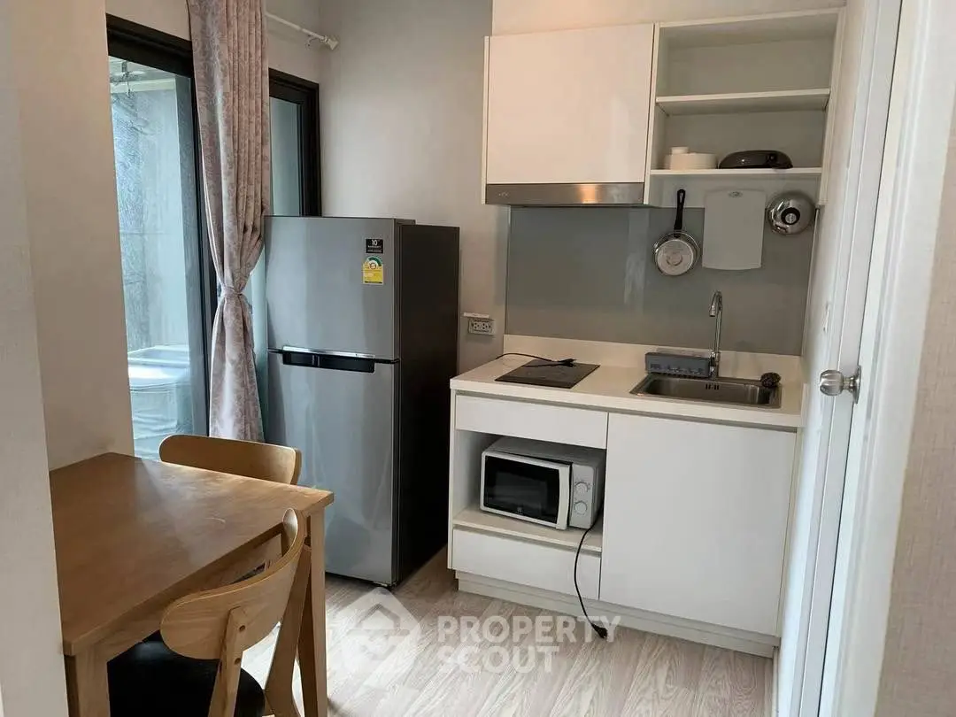 Compact modern kitchen with sleek appliances and dining area, perfect for urban living.
