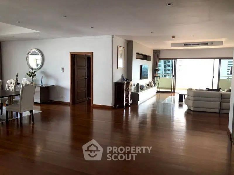 Spacious open-plan living room with elegant dining area and balcony view.