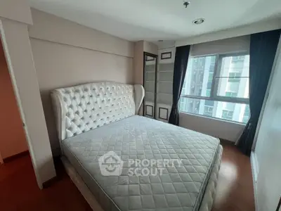 Spacious bedroom with elegant tufted headboard and large window offering natural light.
