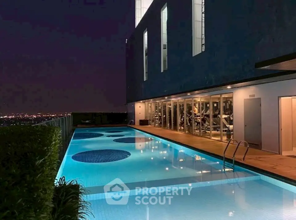 Luxurious rooftop pool with city view and adjacent gym at night