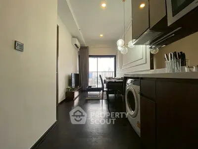 Modern apartment interior with sleek kitchen and cozy living area leading to a balcony with city view.