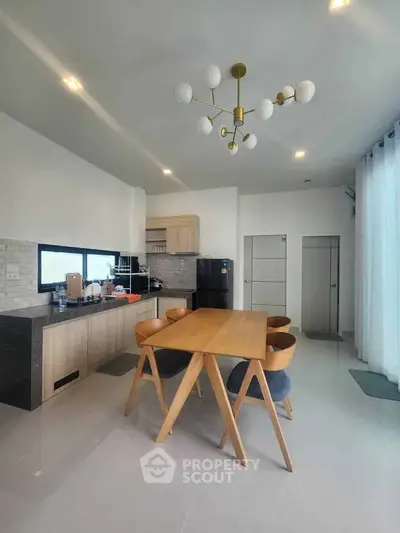 Modern kitchen with sleek design, featuring wooden dining table and stylish lighting fixture.