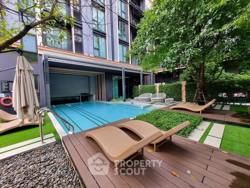 Luxurious condominium pool area with sun loungers and lush greenery, perfect for relaxation.
