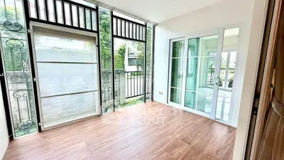 Bright and airy room with large windows and wooden flooring, perfect for a cozy living space.