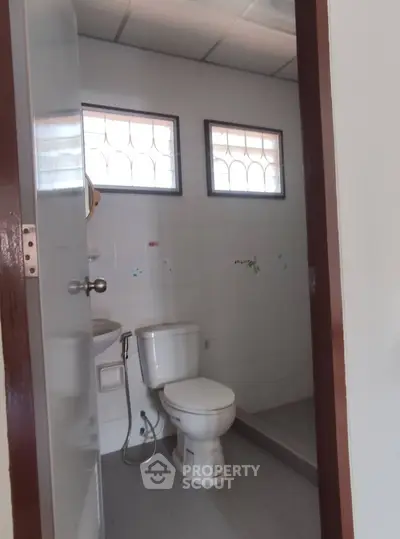 Simple bathroom with toilet and small windows, ideal for compact spaces.
