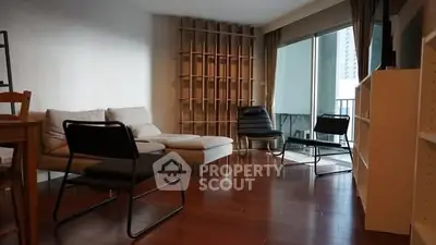 Spacious living room with modern furniture and large windows opening to a balcony.