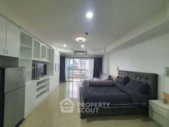 Spacious modern bedroom with balcony and city view, featuring sleek furnishings and ample storage.