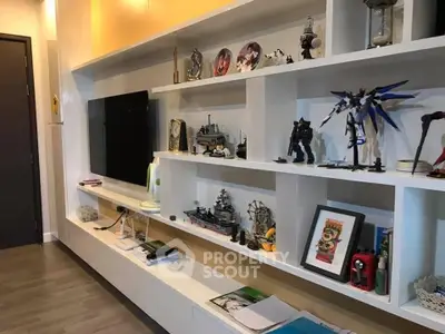 Modern living room with stylish shelving and TV, showcasing collectibles and decor.