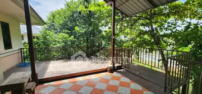 Charming outdoor balcony with lush greenery and wooden deck, perfect for relaxation.