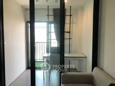 Modern apartment with glass partition and balcony view, featuring sleek furniture and minimalist design.