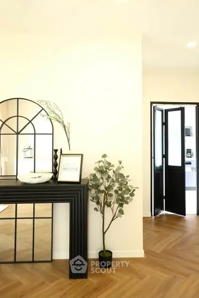 Stylish modern interior with elegant decor and wooden flooring, featuring a decorative mirror and indoor plant.