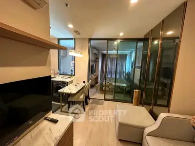 Modern open-plan living room with dining area and glass partitioned bedroom in stylish apartment.