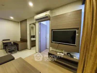 Modern living room with wall-mounted TV and dining area in stylish apartment.