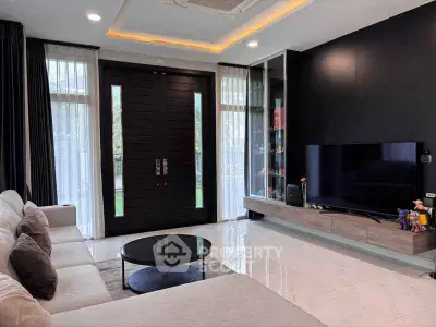 Modern living room with sleek black accents, large TV, and plush seating in a stylish home.