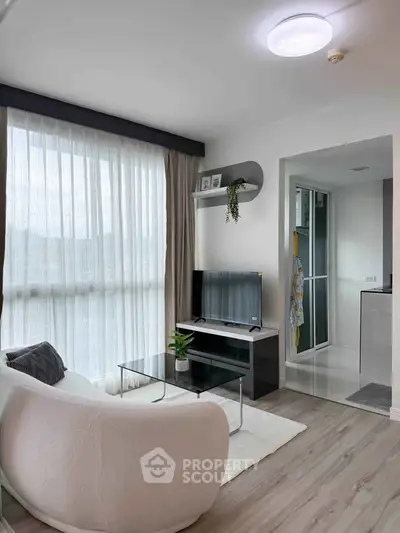 Modern living room with large window, cozy sofa, and sleek TV stand in a bright apartment.
