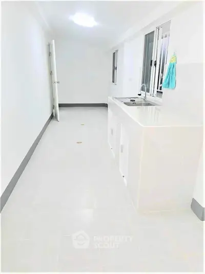 Spacious white kitchen with sleek countertops and ample natural light.