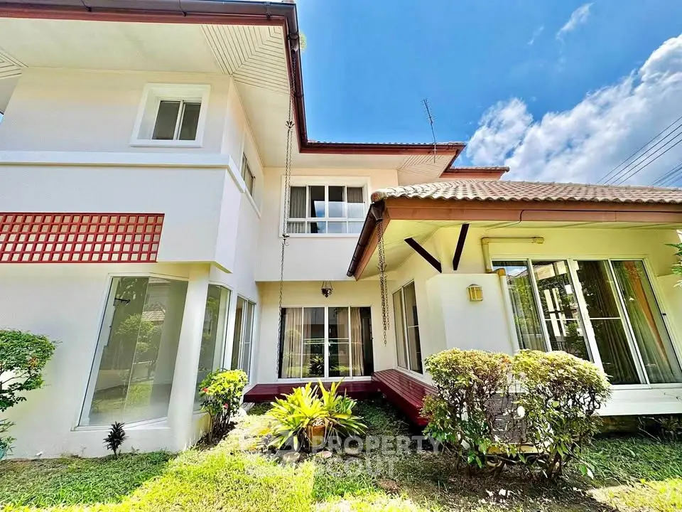 Charming two-story house with lush garden and large windows, perfect for family living.