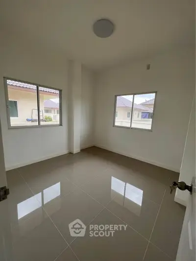 Bright empty room with tiled floor and two windows, ideal for customization.