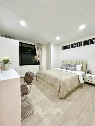 Spacious modern bedroom with elegant decor and large window offering natural light.