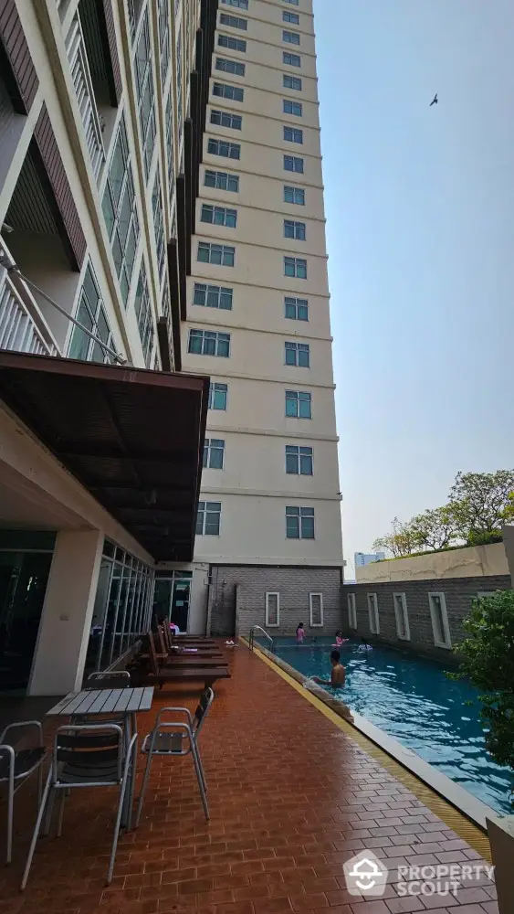 Modern high-rise building with poolside area and swimming pool, perfect for urban living.