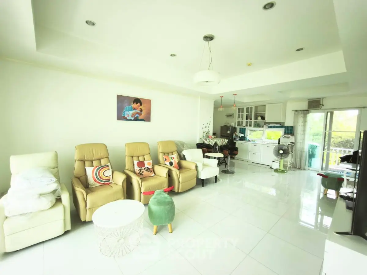 Spacious living room with modern decor and open kitchen layout, featuring comfortable seating and natural light.