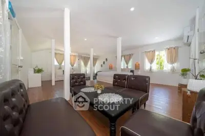 Spacious open-plan living room with elegant leather furniture and abundant natural light
