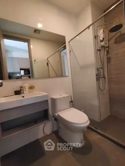 Modern bathroom with glass shower and sleek fixtures in contemporary apartment.