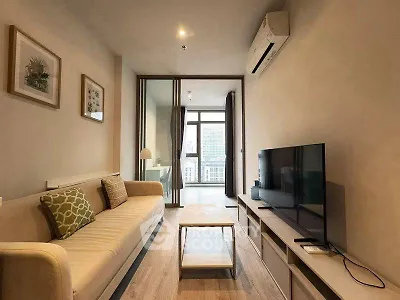Modern living room with sleek design and city view, featuring a comfortable sofa and large TV.