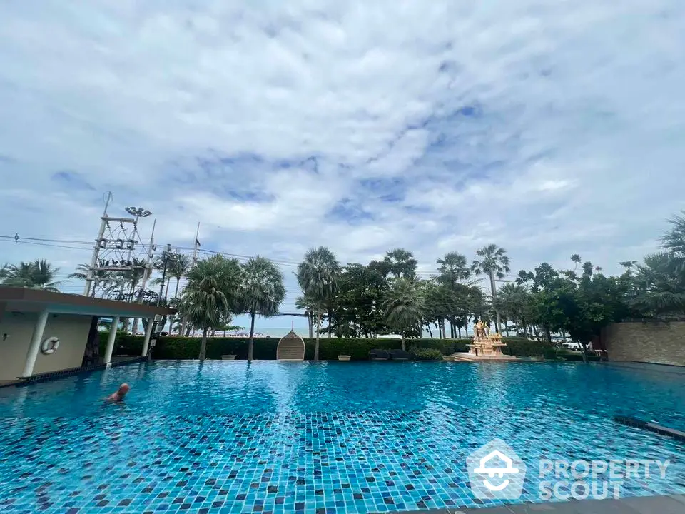 Luxurious outdoor swimming pool with palm trees and serene sky view