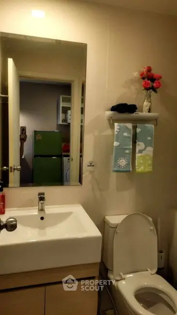 Modern bathroom with sleek sink and toilet, featuring a decorative shelf and mirror.