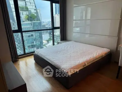 Modern bedroom with large windows offering stunning city views in a high-rise apartment.