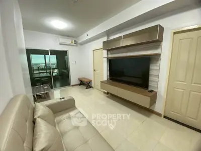 Modern living room with sleek TV unit and balcony view in stylish apartment.