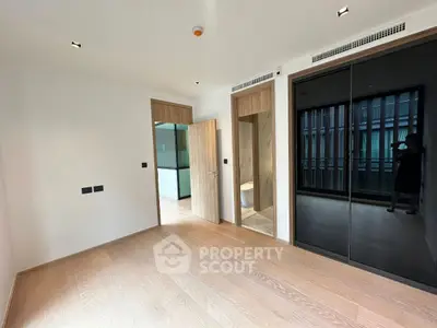Spacious modern bedroom with wooden flooring and built-in wardrobe in luxury apartment.