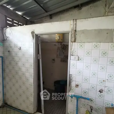 Rustic bathroom with vintage tiles and exposed pipes in need of renovation.