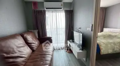 Cozy living room with leather sofa and natural light, adjacent to a bedroom.